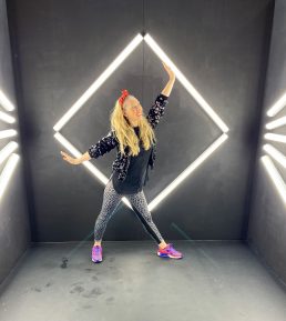 Dance teacher posing infront of a glow up diamond shape