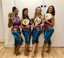 Four female dancers holding score paddles