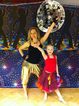 Party teacher and girl posing next to a big glitter ball