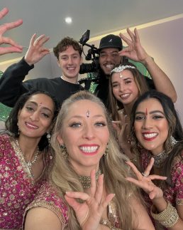 Four Bollywood dancers posing with two camera men