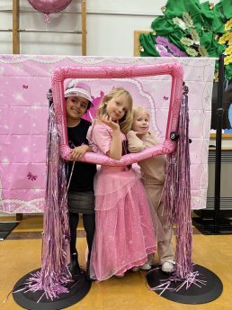 Three girls posing in a Barbie frame